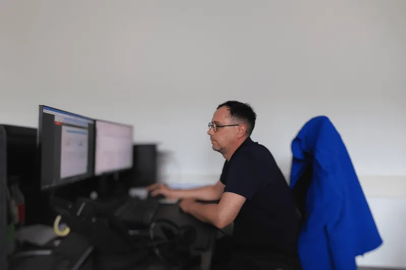 Mann arbeitet konzentriert am Computer mit zwei Monitoren im modernen Büroalltag.